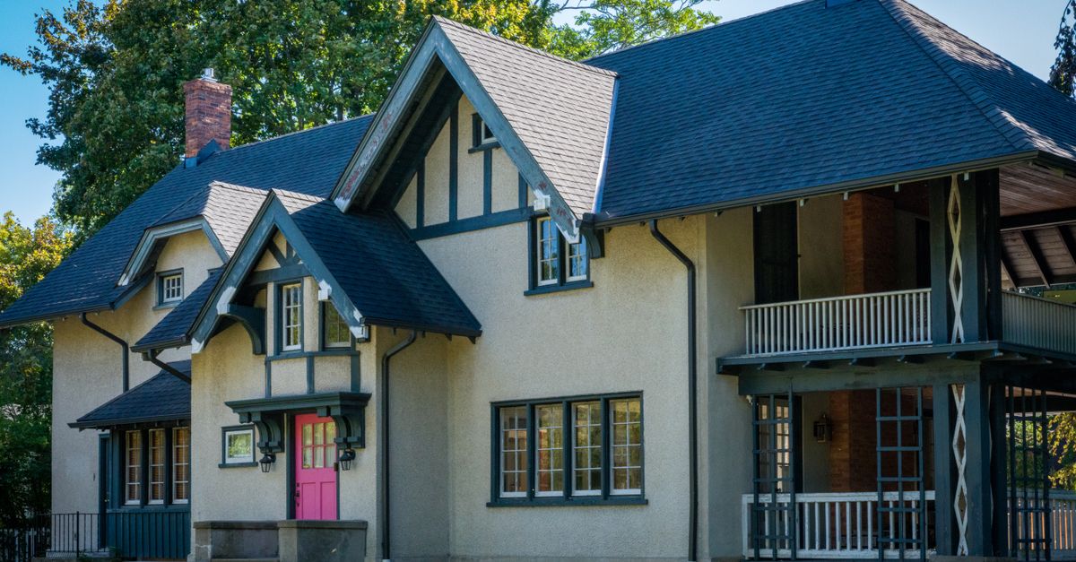 Beautiful Tudor-style home with vibrant pink door surrounded by greenery.