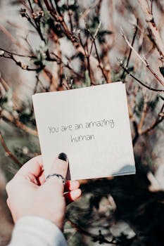 手拿一张鼓舞人心的语录卡，站在户外的自然背景中