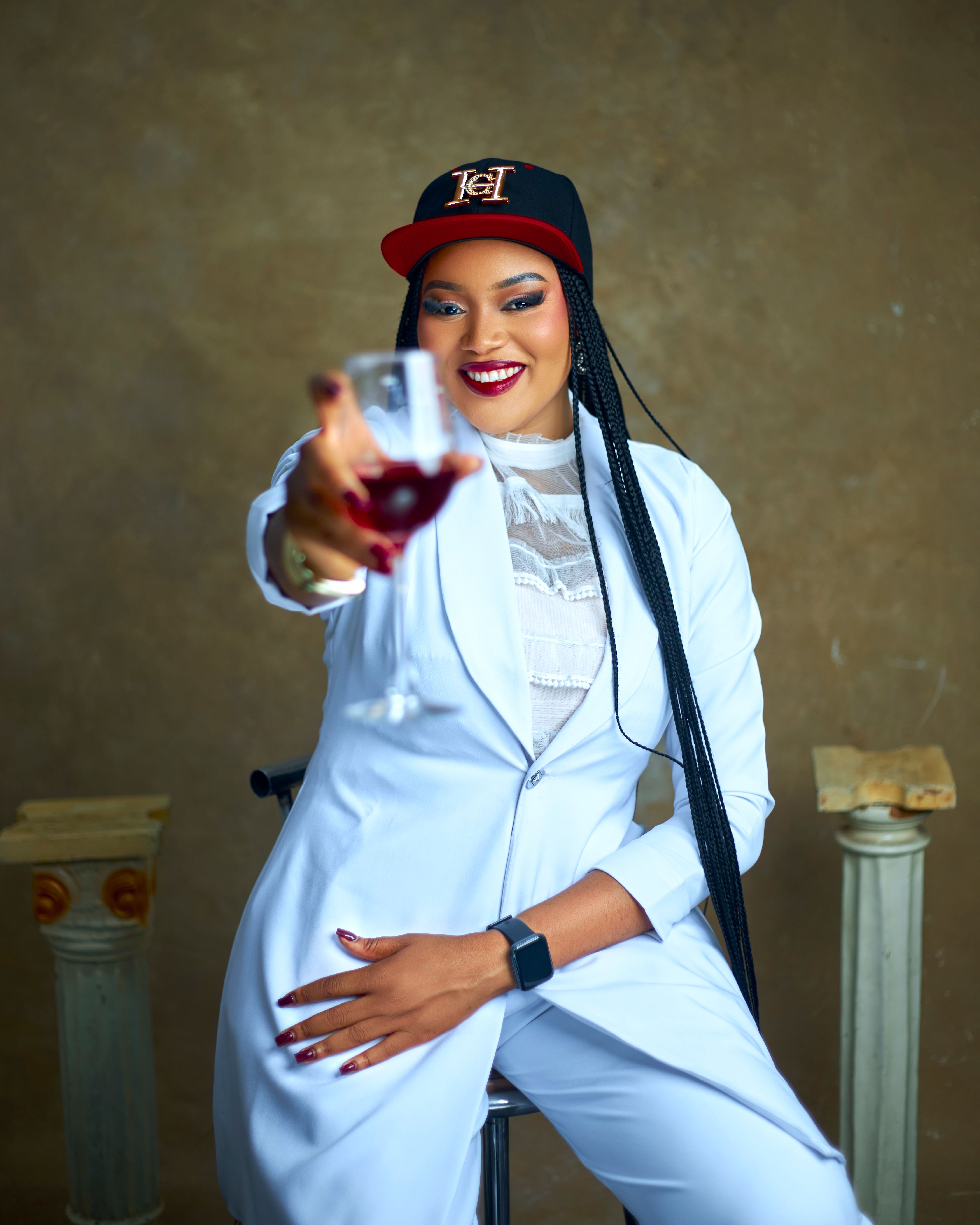 Cheerful woman in a white suit offering a toast indoors with a smile.