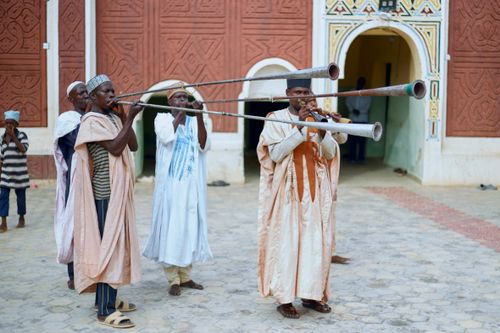 Free Group of traditional musicians playing long horns in cultural attire outdoors. Stock Photo