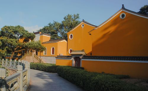 Free Scenic view of bright orange traditional Asian buildings with trees and walkway on a sunny day. Stock Photo