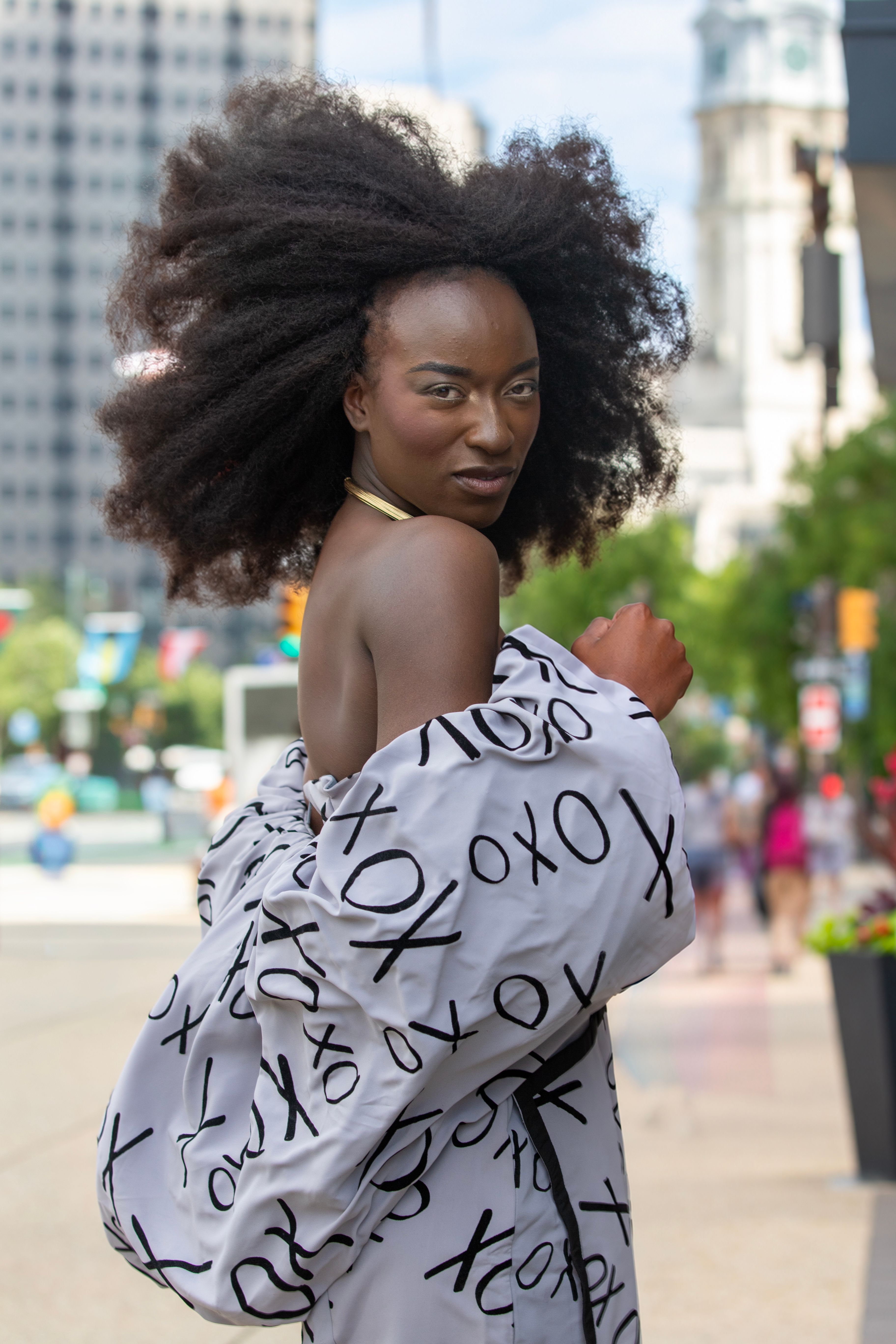 Elegant portrait of a woman with afro hair in a fashionable outfit on a city street in Philadelphia.