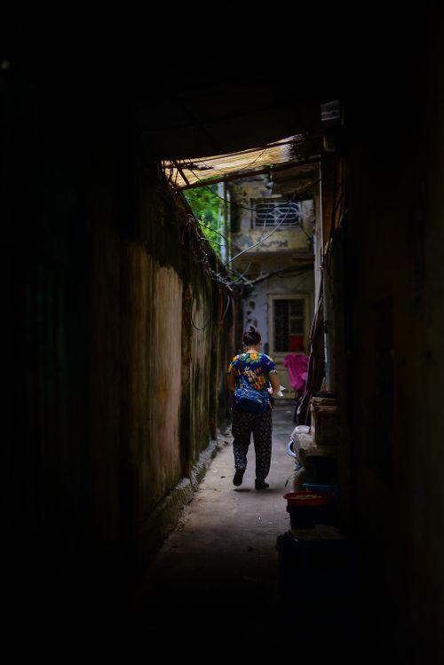 Free A lone person walks through a narrow urban alleyway, dimly lit with an atmospheric feel. Stock Photo