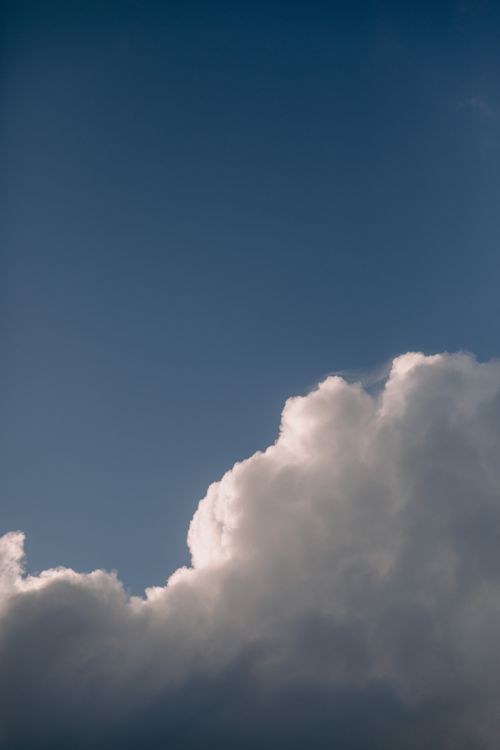 Free Fluffy white clouds with a silver lining set against a vibrant blue sky, capturing nature's beauty. Stock Photo