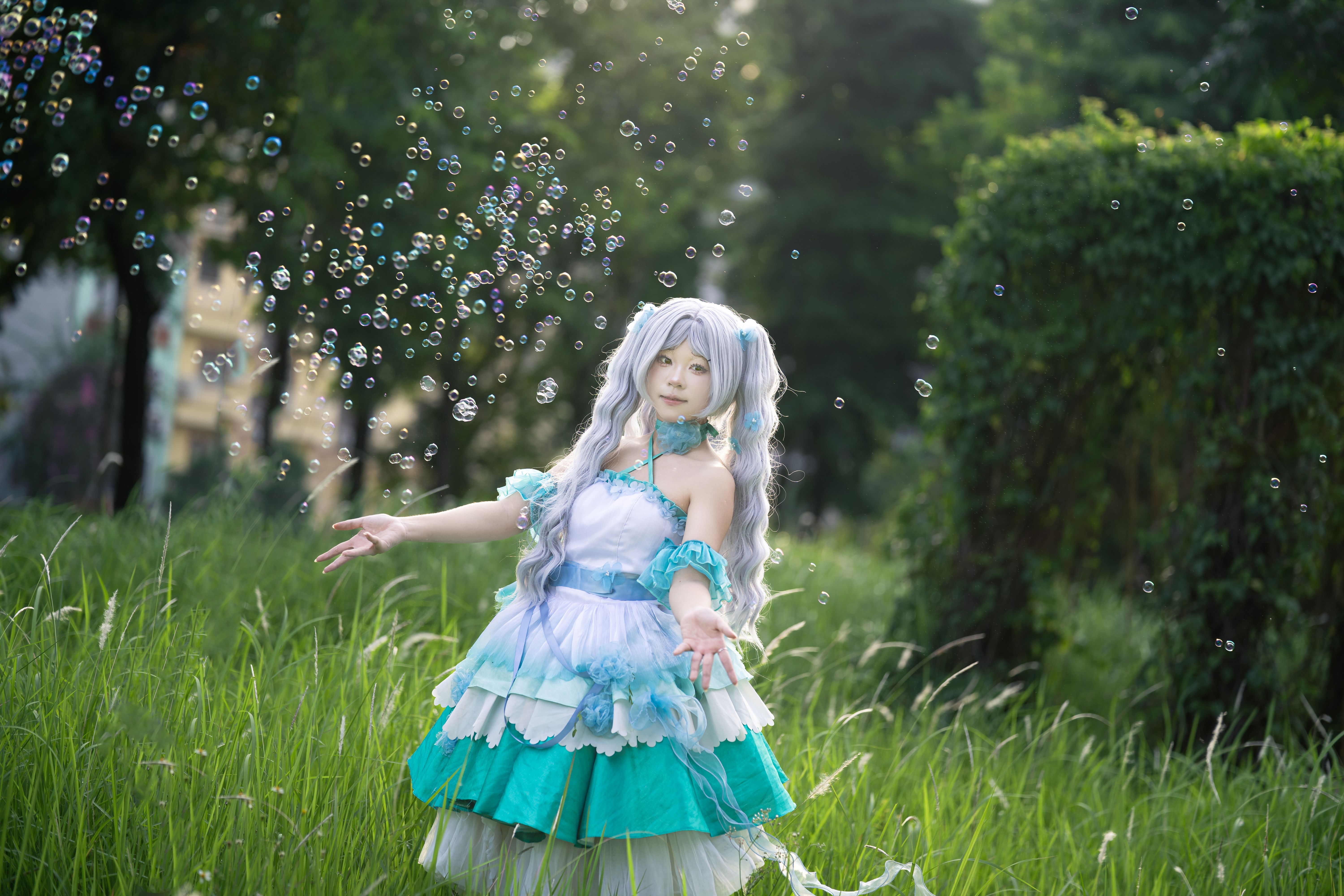Cosplayer in elegant dress amidst bubbles in a serene outdoor setting.