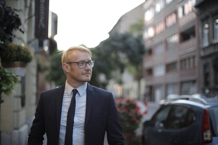 Confident Male Executive Standing Against Modern Buildings In Street