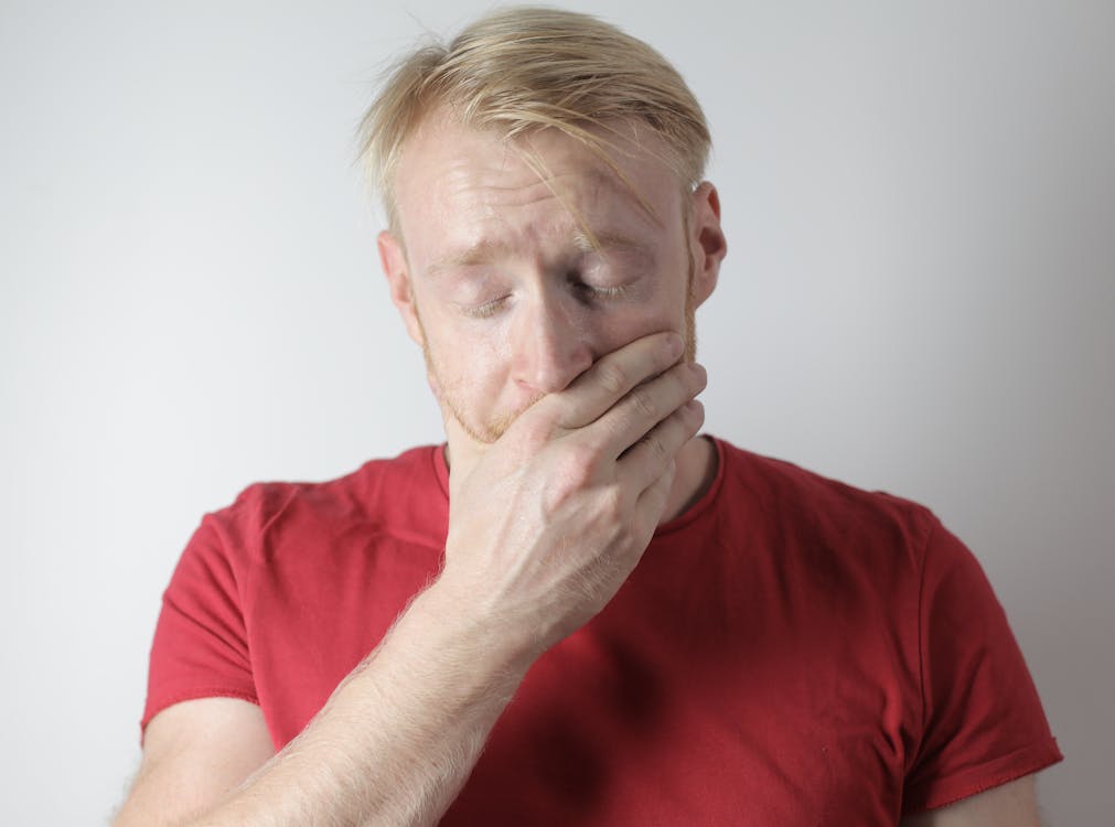 Free Mature man in red t shirt being in shock after getting news standing with closed eyes near gray wall in room Stock Photo