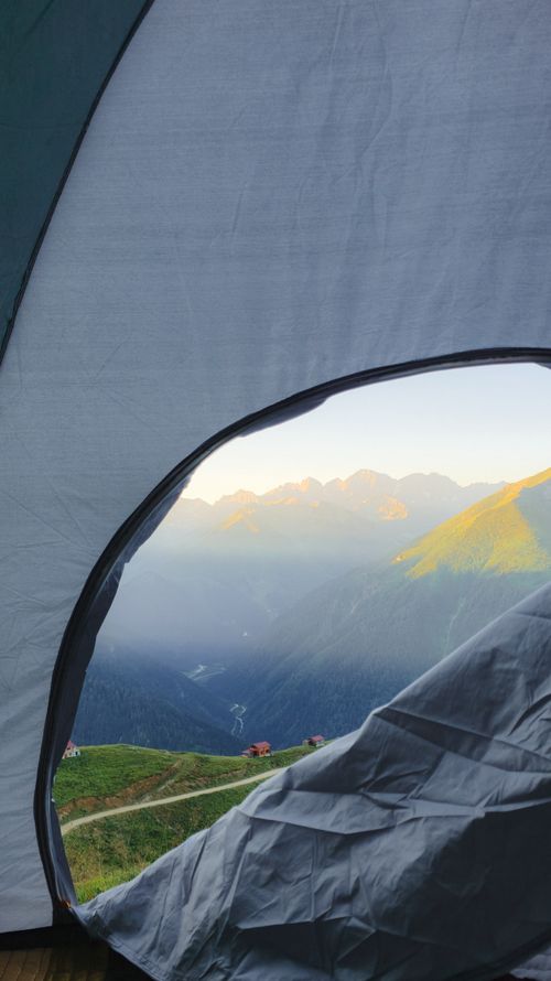 Free Experience a stunning mountain sunrise from a tent, capturing nature's serene beauty. Stock Photo