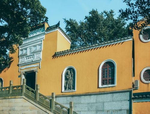 Free Vibrant yellow Chinese temple facade with intricate details and trees. Stock Photo