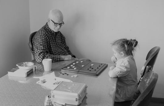 一张祖父母和孙子在室内玩棋盘游戏的黑白照片