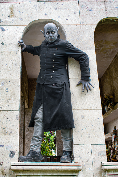 Free Eerie vampire character posing in a stone archway, creating a gothic and dramatic atmosphere. Stock Photo