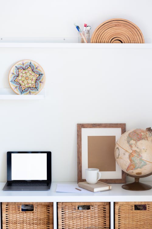 Vintage furniture with empty frame and blank screen of netbook in light room