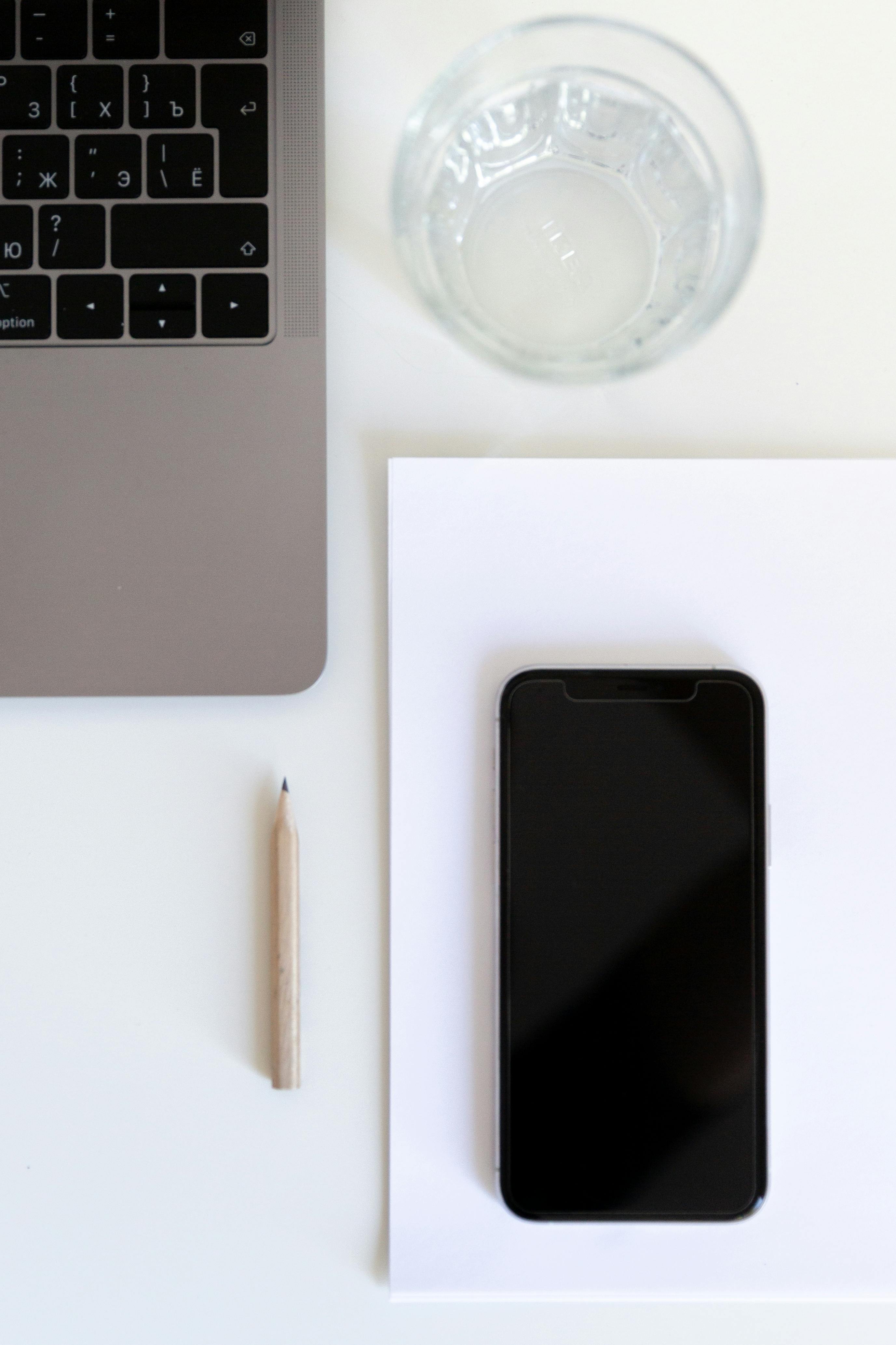 freelance table with glass of water laptop mobile phone and pencil