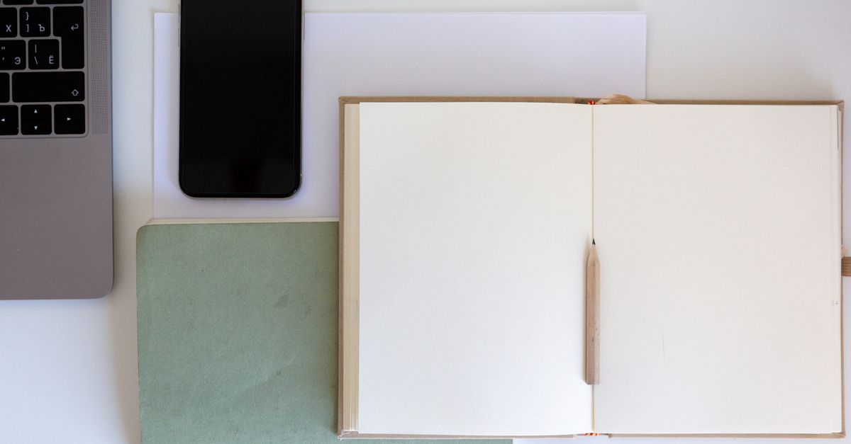 A serene, tidy desk with a laptop open to a focused writing app, phone face down and out of frame