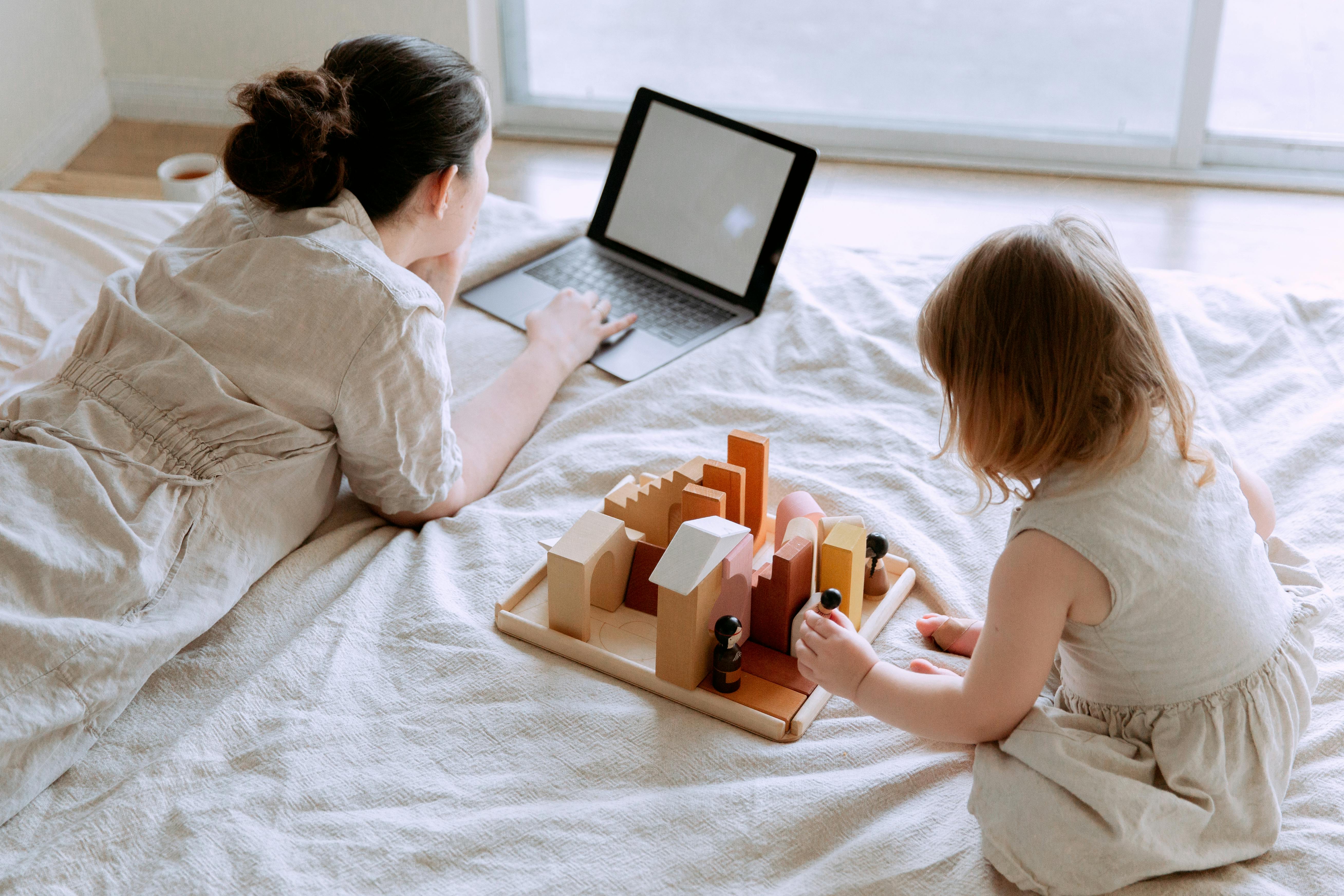 woman on the bed using a laptop with a little girl