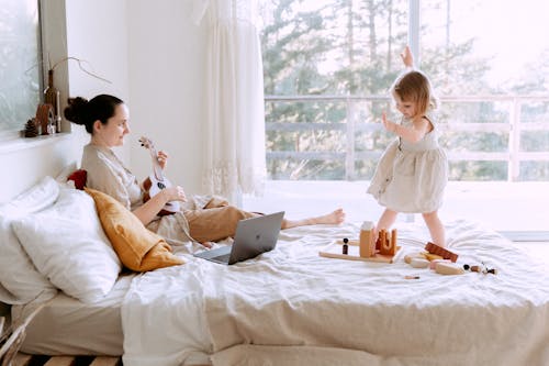 Happy young woman playing ukulele for daughter at home