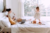 一位快乐的母亲弹着尤克里里，她的女儿在阳光明媚的卧室里跳舞