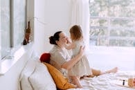 Mother and daughter having fun in bedroom while spending time together at home