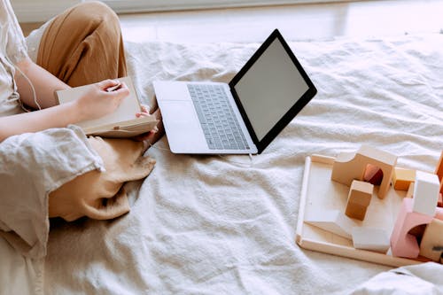 Crop woman using laptop on bed