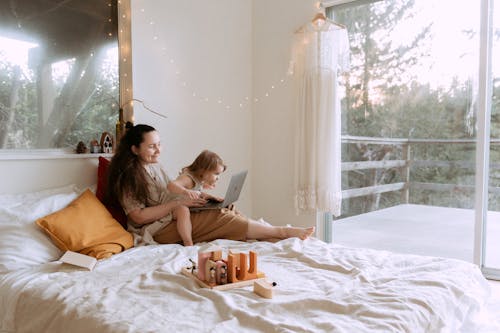 Woman with small girl cheerfully using laptop