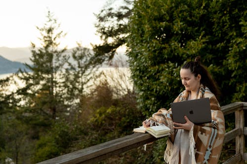 Free Calm freelancer with laptop and book on balcony near mountains Stock Photo