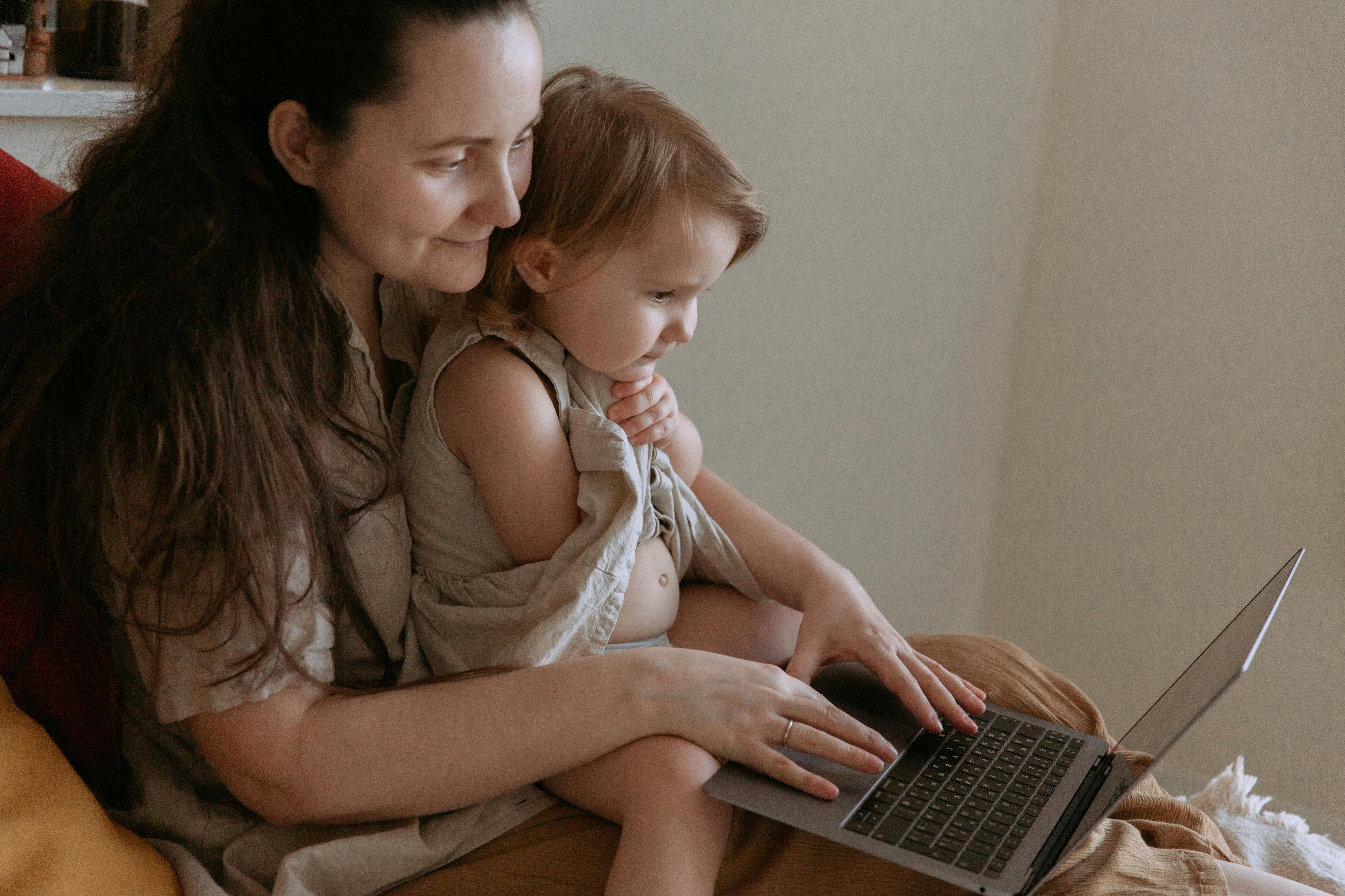 crop mother with little daughter using social media on laptop