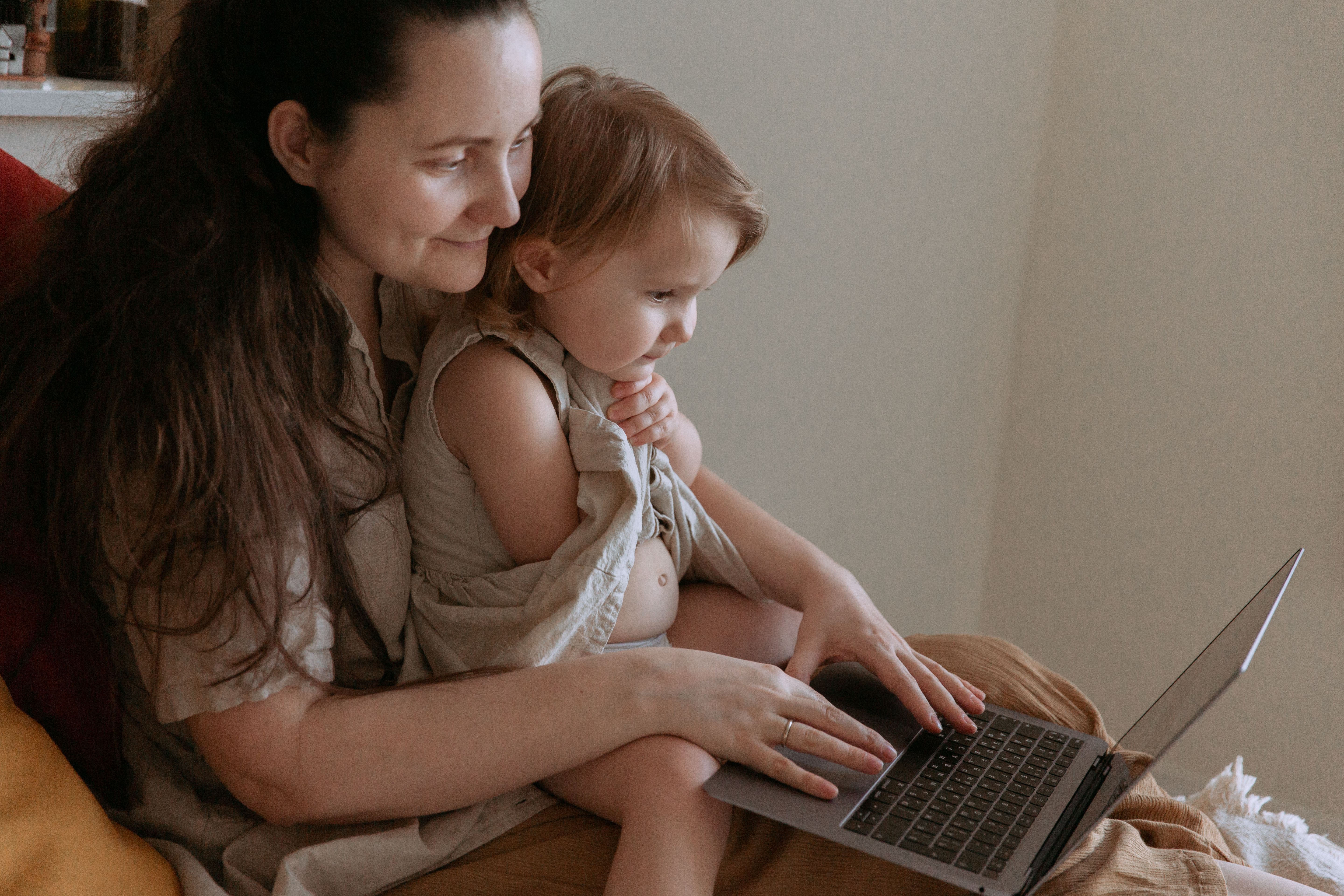 A child in a mother's lap watching a laptop