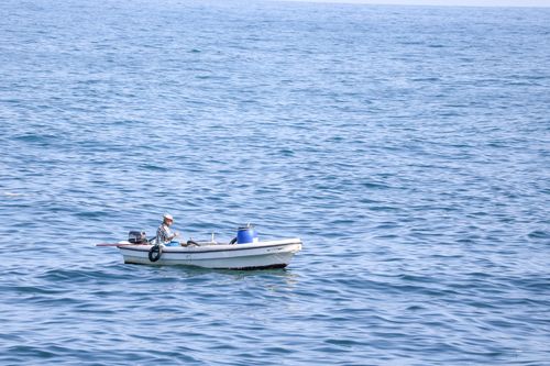 Free A lone fisherman in a small boat fishing on the calm Mediterranean Sea, Beirut, Lebanon. Stock Photo