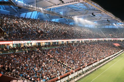 Free Crowd fills a vibrant soccer stadium at night with bright lights and a lively atmosphere. Stock Photo