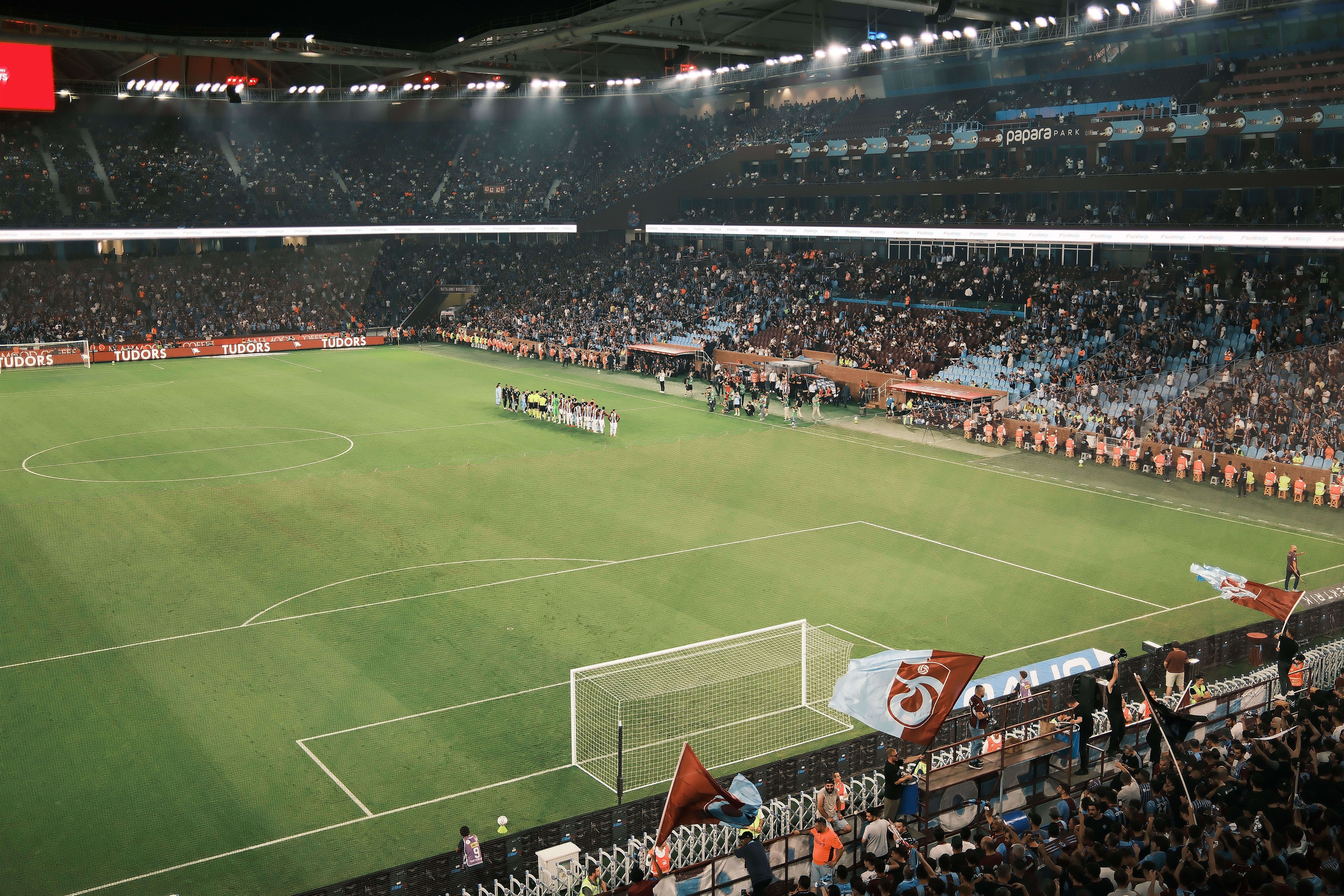 Estadio abarrotado durante un emocionante partido de fútbol nocturno, con un público vibrante y una vista del campo espectacular.