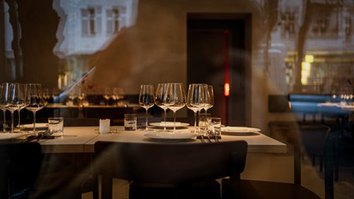 Free Modern restaurant interior featuring elegantly set tables with wine glasses and subtle lighting. Stock Photo