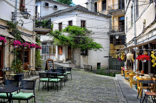 Free Discover a picturesque street in Gjirokastër, Albania, featuring cozy outdoor cafes and vibrant plants. Stock Photo