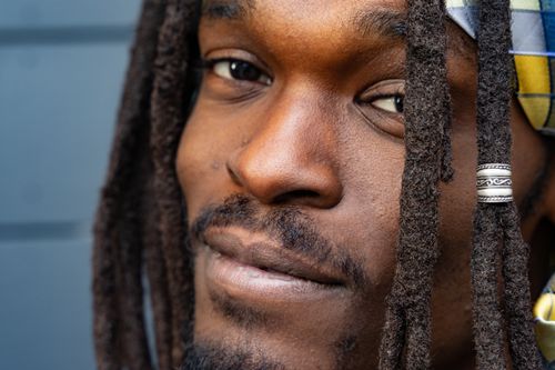Free Intimate close-up portrait showcasing a man's face adorned with dreadlocks and a colorful bandana. Stock Photo