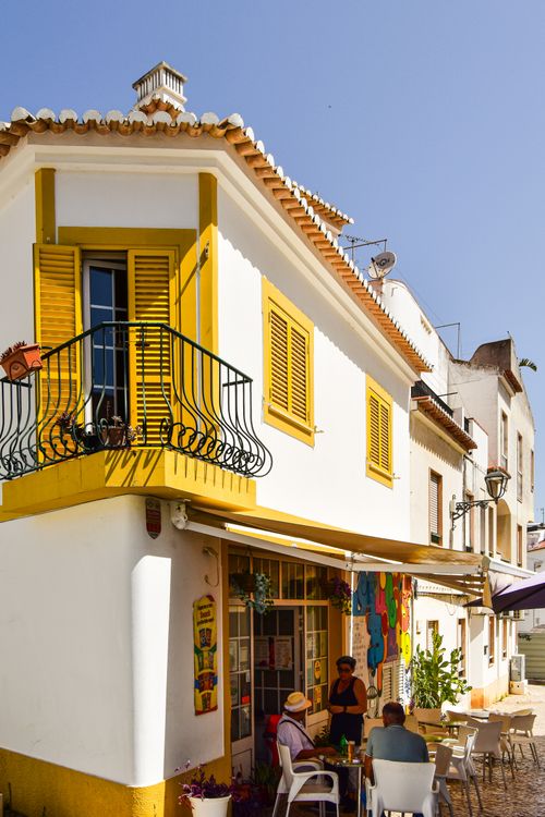 Free A quaint café corner in Faro District, Portugal captures vibrant local charm in warm sunlight. Stock Photo