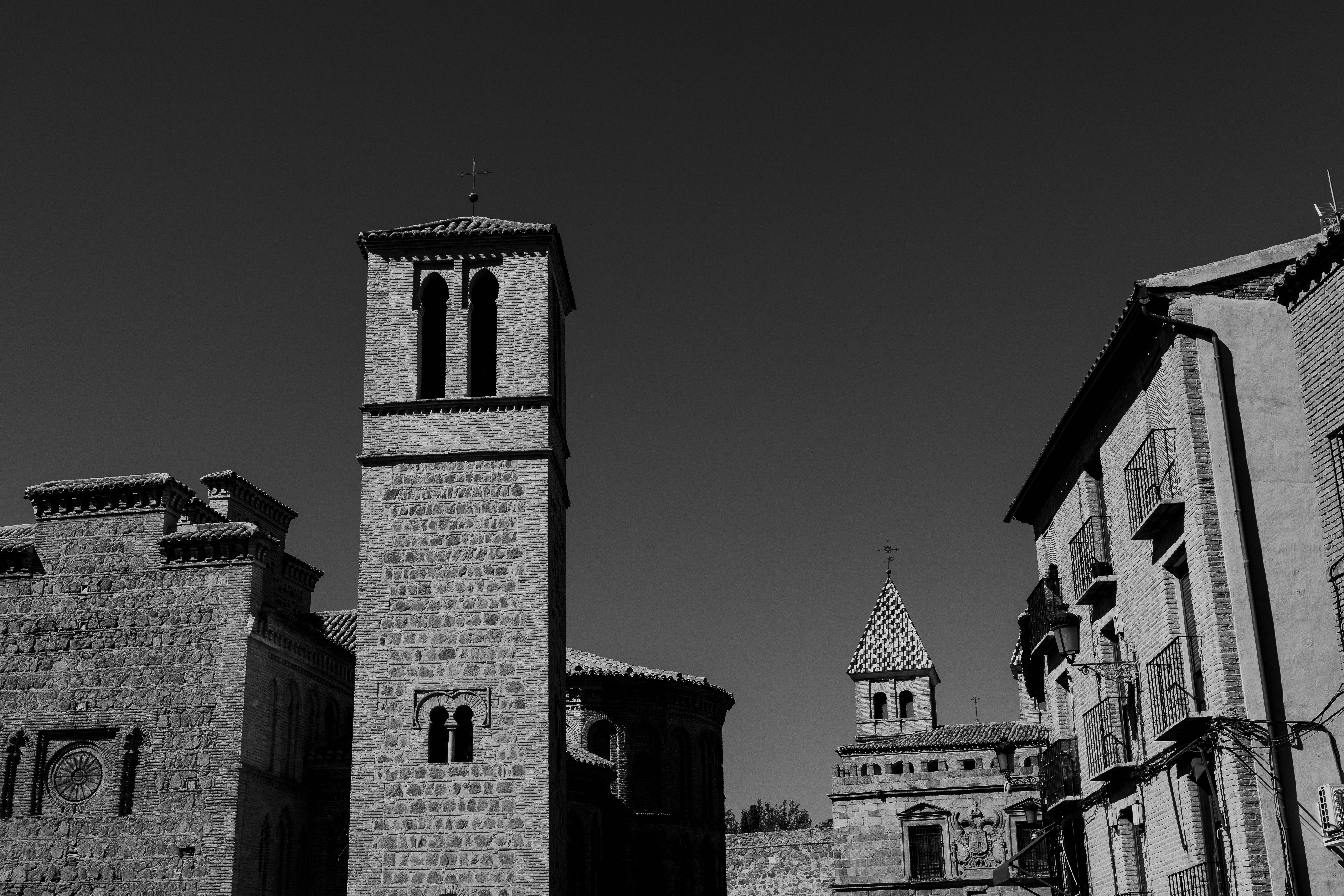 Black and white photo of historic architecture in Toledo, Spain, featuring stone buildings and towers.