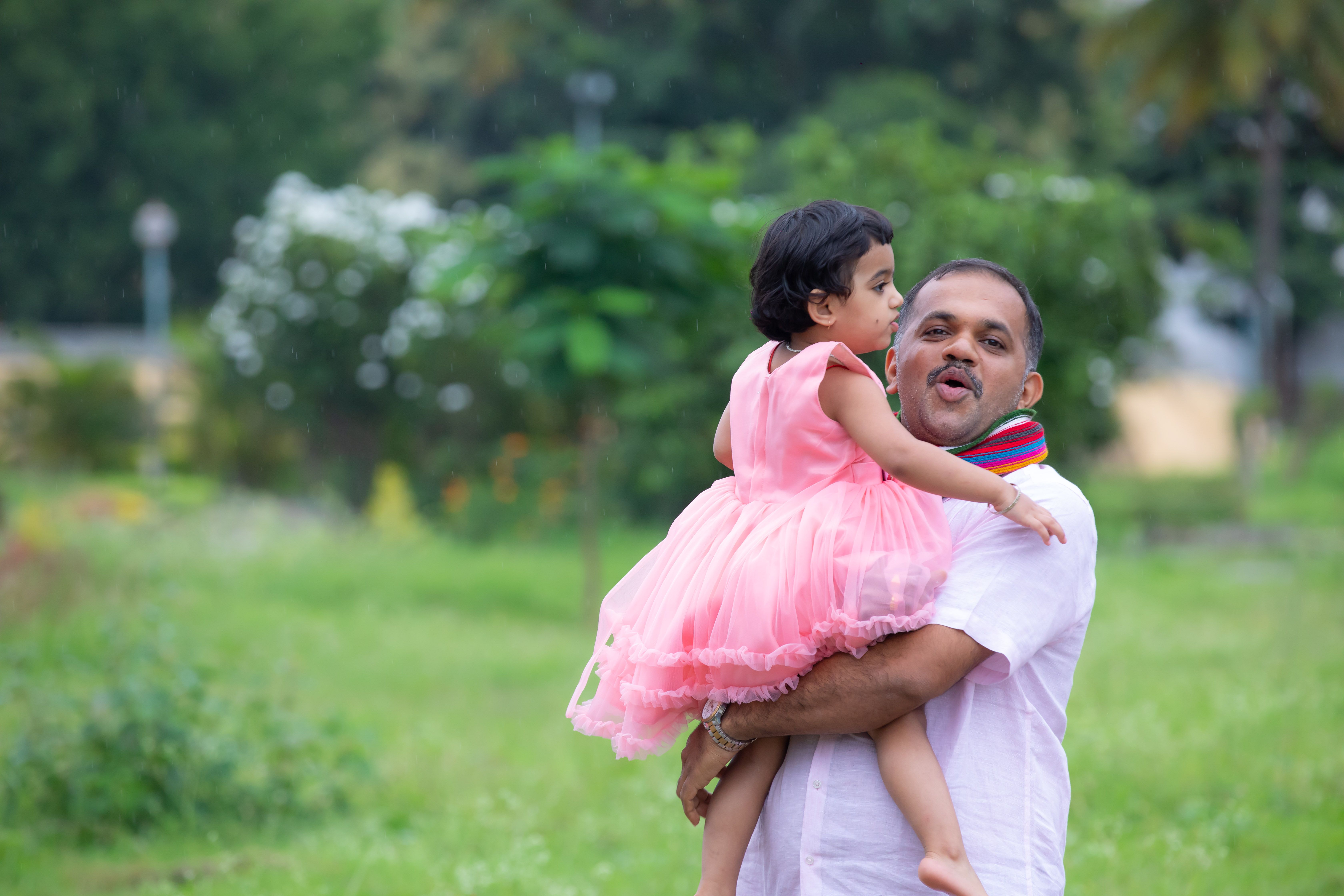 Joyful father and daughter bonding outdoors in a lush green park on a bright day.