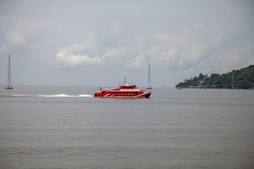 Free A striking red ferry moves across calm waters with a cloudy sky backdrop. Stock Photo
