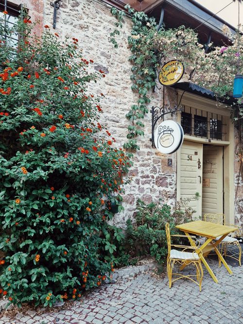 Free Vintage café facade in Balıkesir, Türkiye, with rustic stone walls and vibrant flowers. Stock Photo