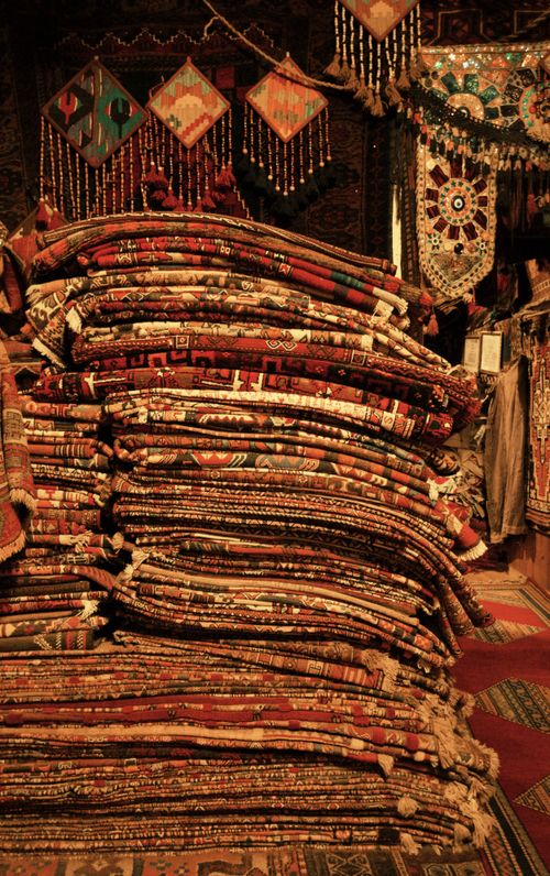Free Colorful Oriental carpets stacked in a traditional shop setting, capturing rich cultural artisan textures. Stock Photo