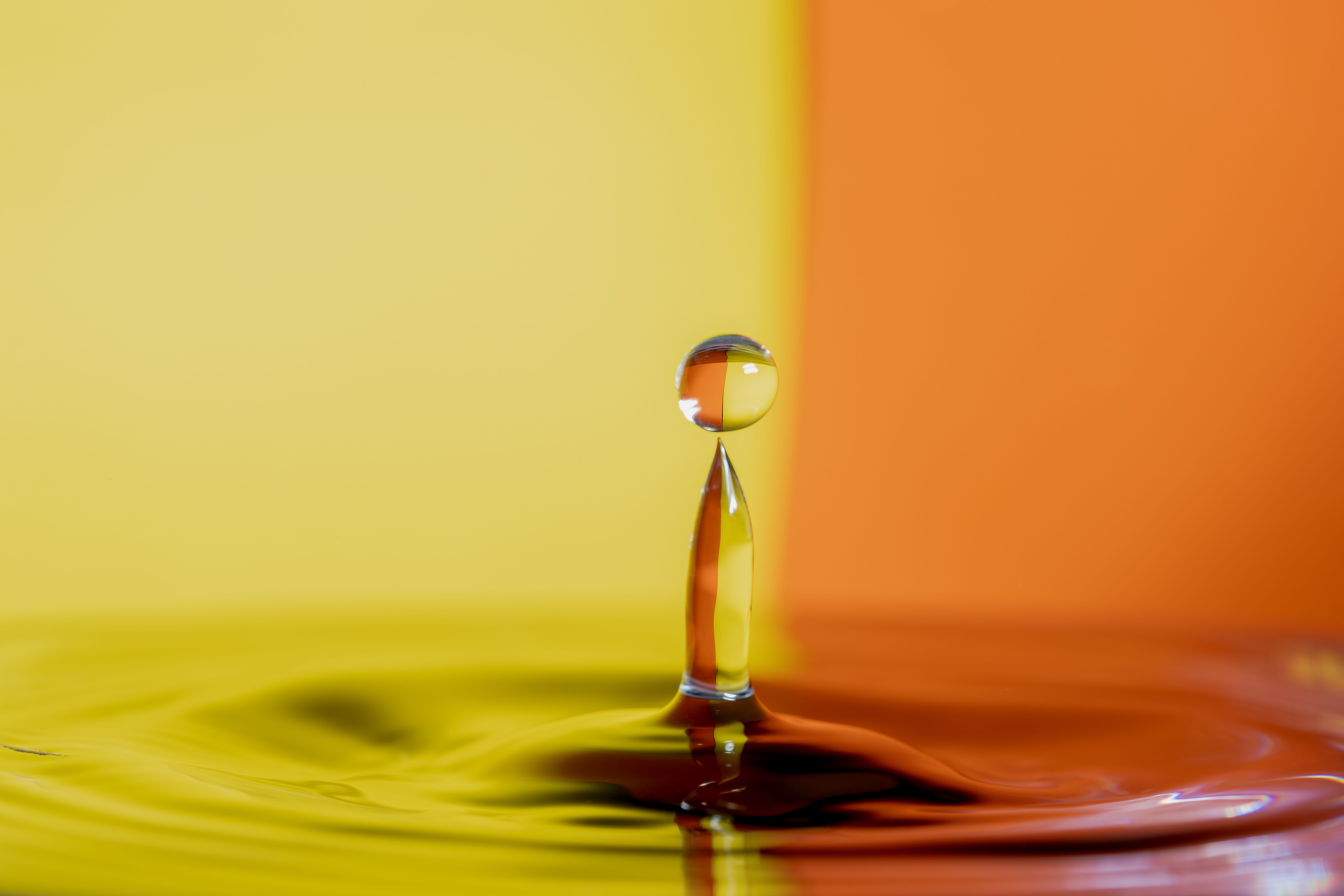 Fotomural Dramática fotografía macro de una gota de agua sobre un fondo de vibrantes tonos amarillos y naranjas.