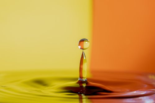 Free Dramatic macro shot of a water droplet against a vibrant yellow and orange backdrop. Stock Photo