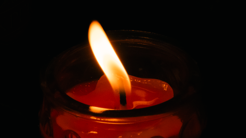 Free A close-up image of a candle with a flame glowing in the dark, creating a warm ambiance. Stock Photo