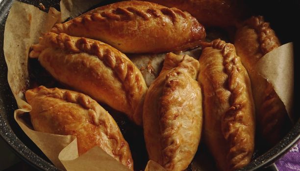 Delicious golden-brown empanadas freshly baked in a rustic pan.