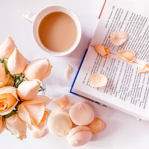 Free Relaxed morning setup with a coffee mug, a book, and peach roses. Stock Photo