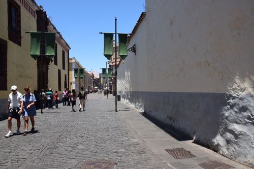 Free A sunny day on a historic cobblestone street lined with green banners and pedestrians in the city. Stock Photo