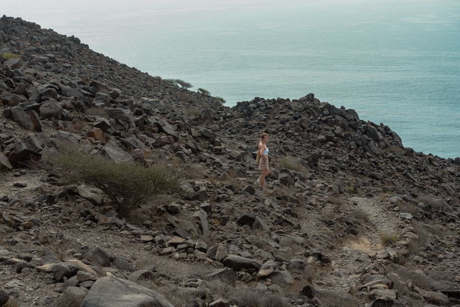 A lone traveler explores the rocky landscape overlooking the Gulf of Oman in Khor Fakkan, UAE.