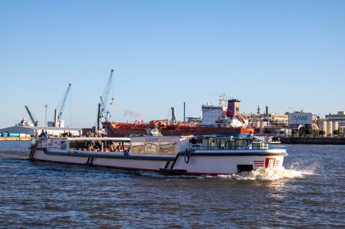 Free Tourist boat cruising through the bustling Hamburg port on a sunny day. Stock Photo