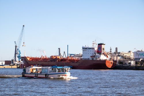 Free A cargo ship and tour boat navigating Hamburg Port under a clear blue sky. Stock Photo