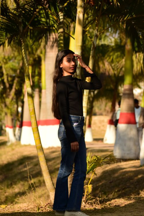 Free Casual outdoor portrait of a young woman amidst palm trees in India, showcasing natural sunlight. Stock Photo
