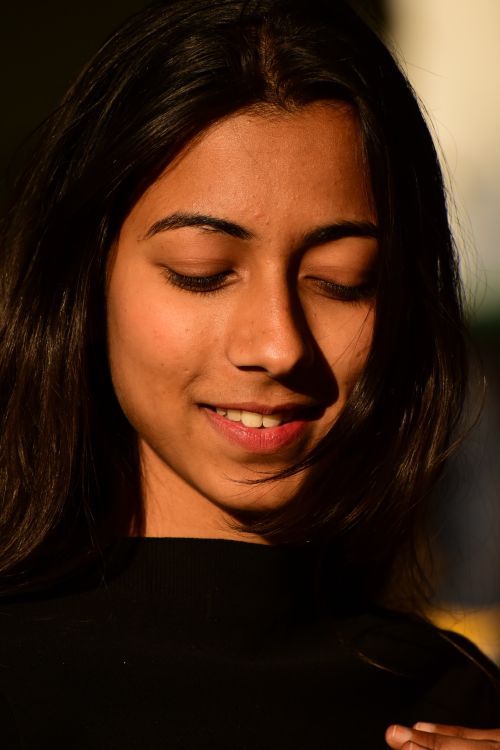 Free A warm portrait of a smiling woman in natural light, showcasing serene beauty and elegance. Stock Photo